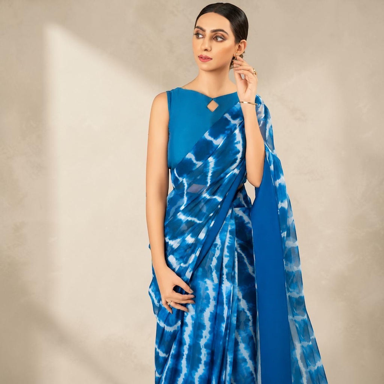 Zarfina digital printed blue chiffon saree with a matching raw silk sleeveless blouse for formal occasions.