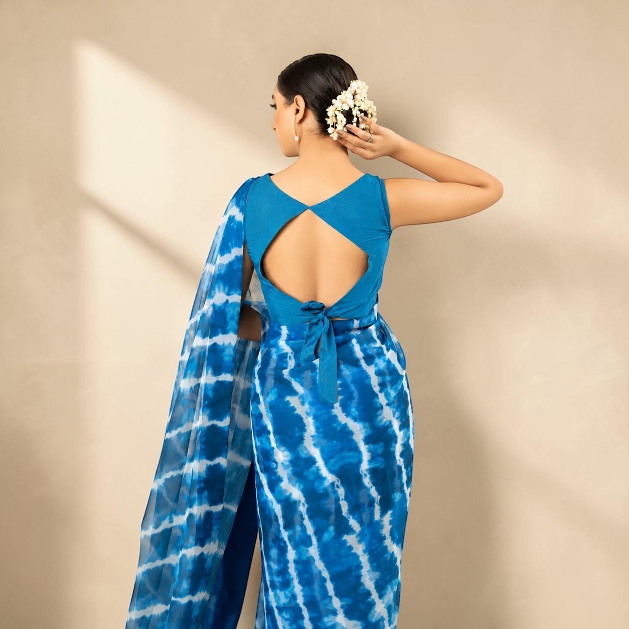 Zarfina digital printed blue and white chiffon saree with a raw silk sleeveless blouse featuring a back tie detail.